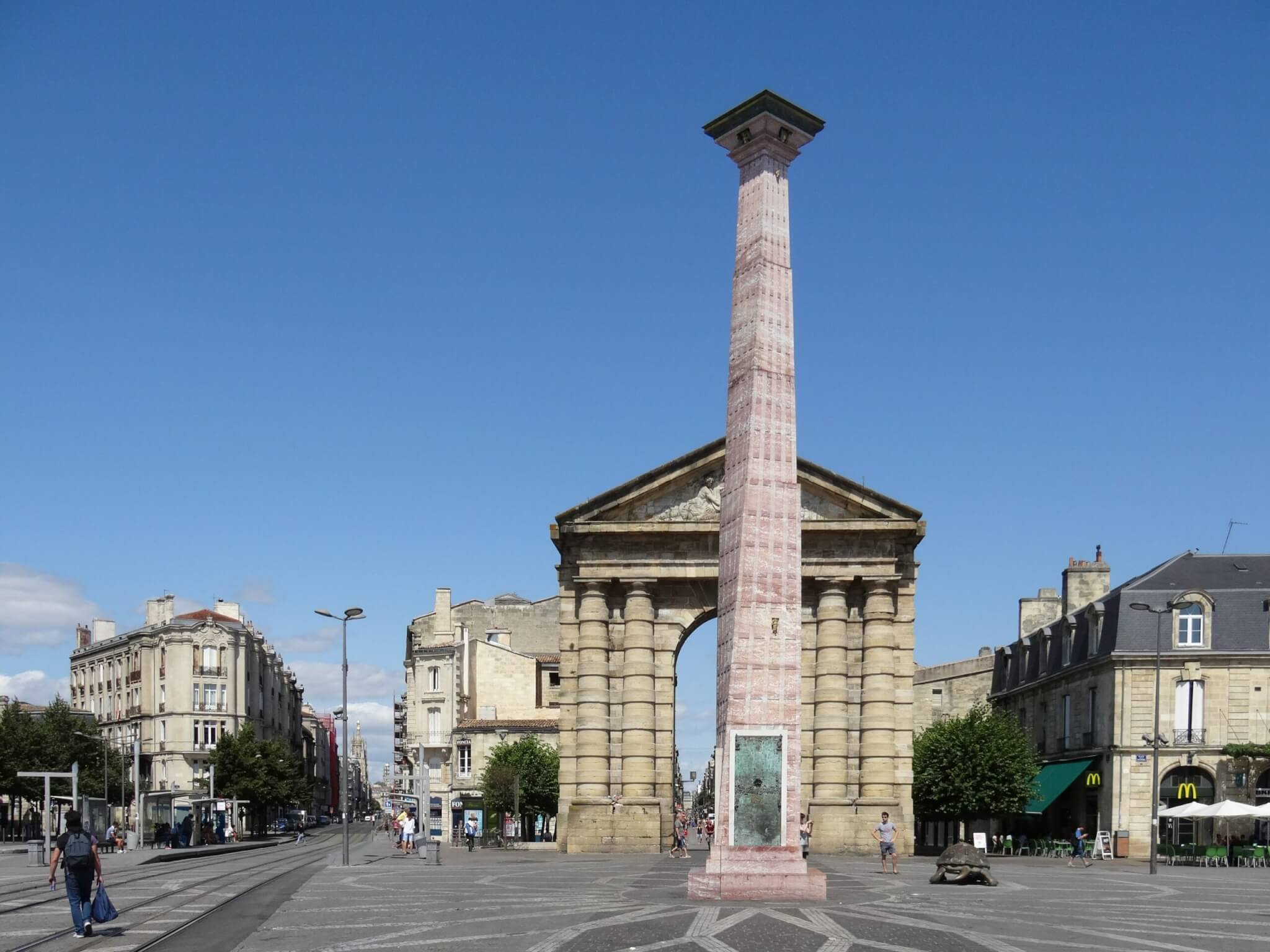Stadspoort vormgegeven als Romeinse triomfboog met fronton en zuilen. Op de voorgrond een gedraaide obelisk