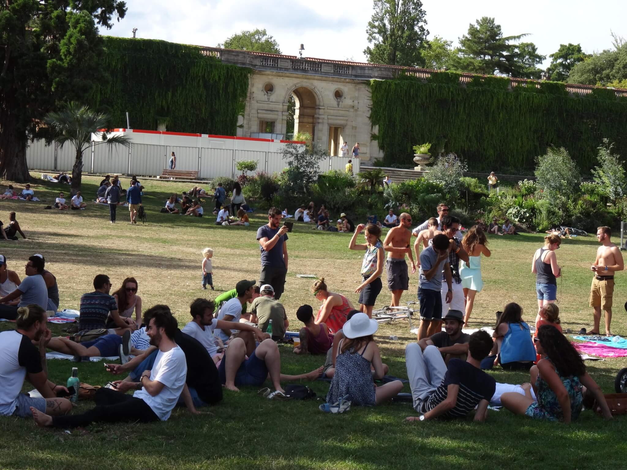Picknickende Bordelezen op het gazon van Jardin Publique. Op de achtergrond een neoklassieke muur bedekt met klimop