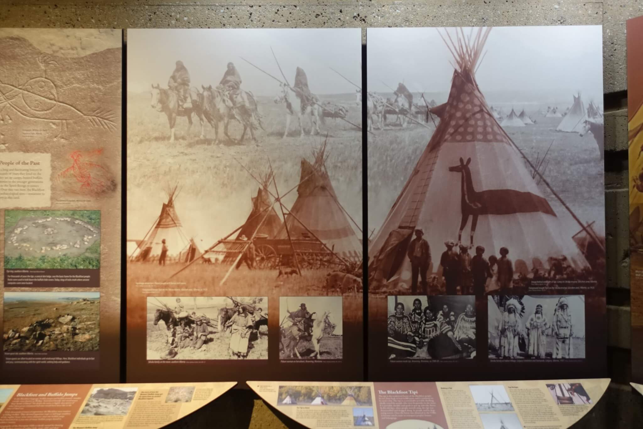 Zwart-wit foto's op de wand tonen Blackfootindianen op paarden en rond tipi's
