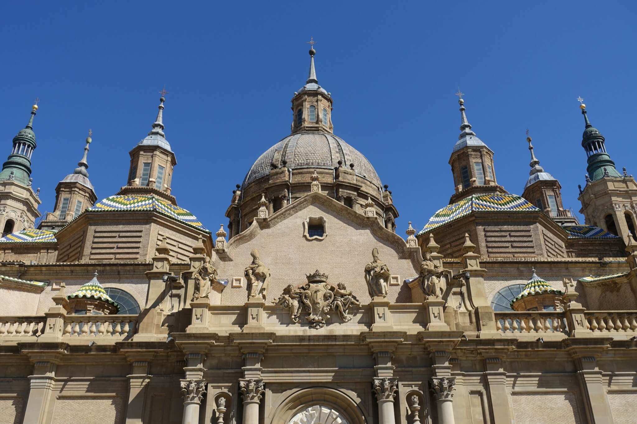 Fronton kathedraal Zaragoza met wapenschild en heiligen omringd door vele torentjes en een koepel