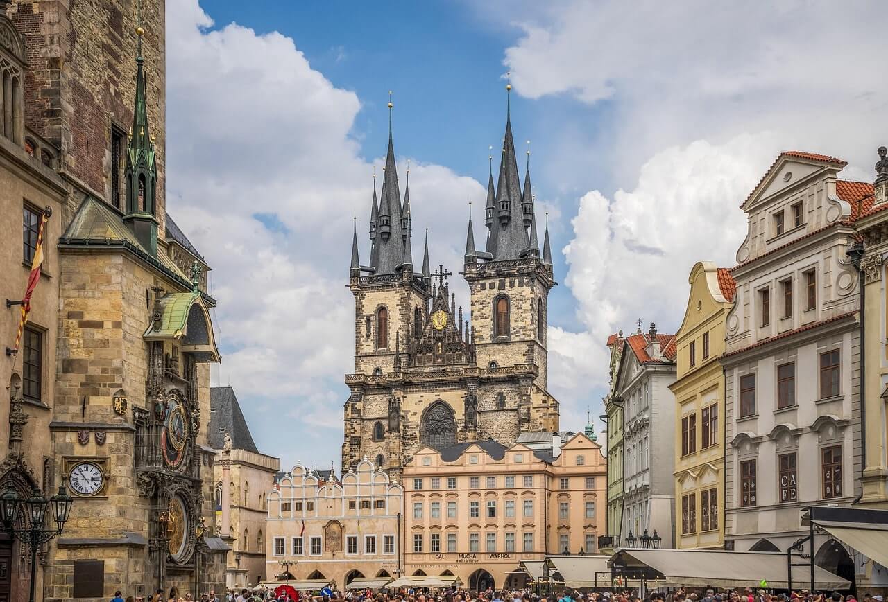 Gotische torenspitsen vol kleine torentjes steken hoog uit boven kleurrijke barokgevels aan oudestadsplein Praag