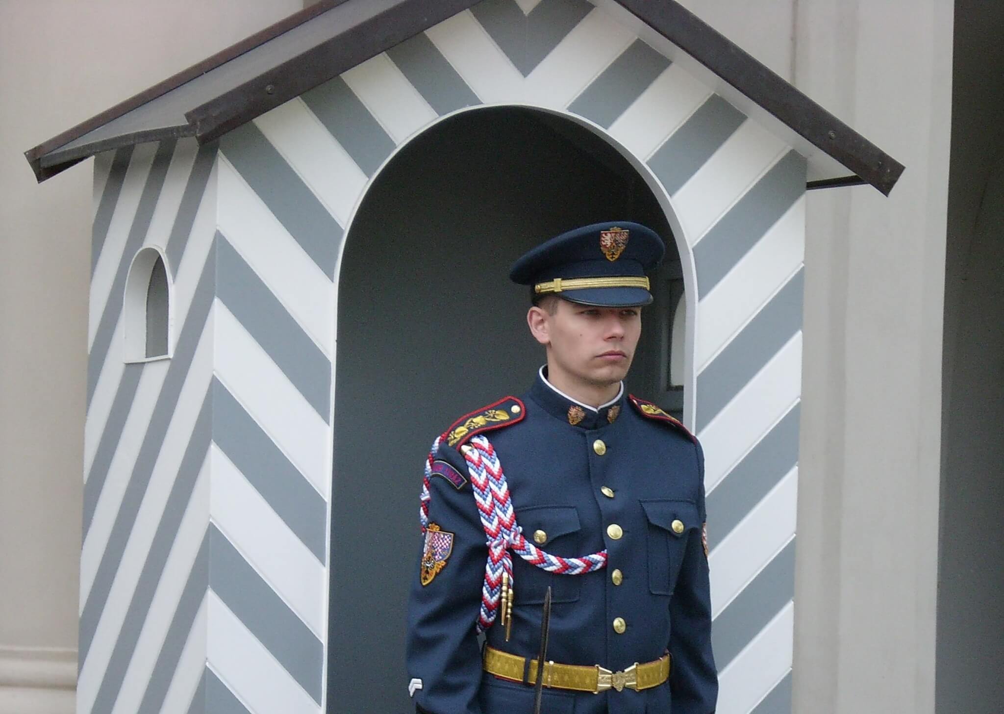 Strak voor zich uitkijkende paleiswacht voor zijn grijs-wit gestreepte hokje in Praag