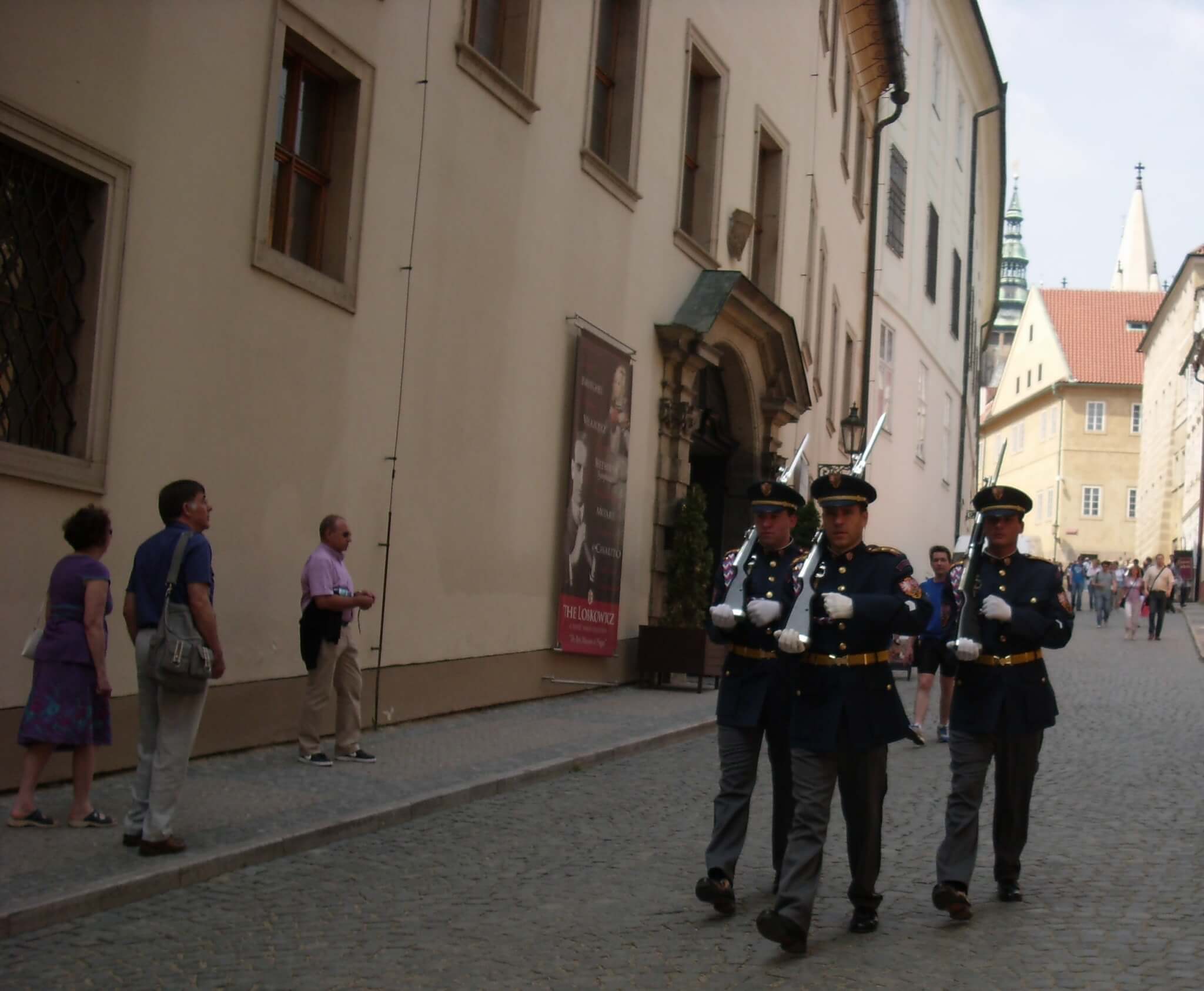 Drie geüniformeerde paleiswachten marcheren door de straten van Praag