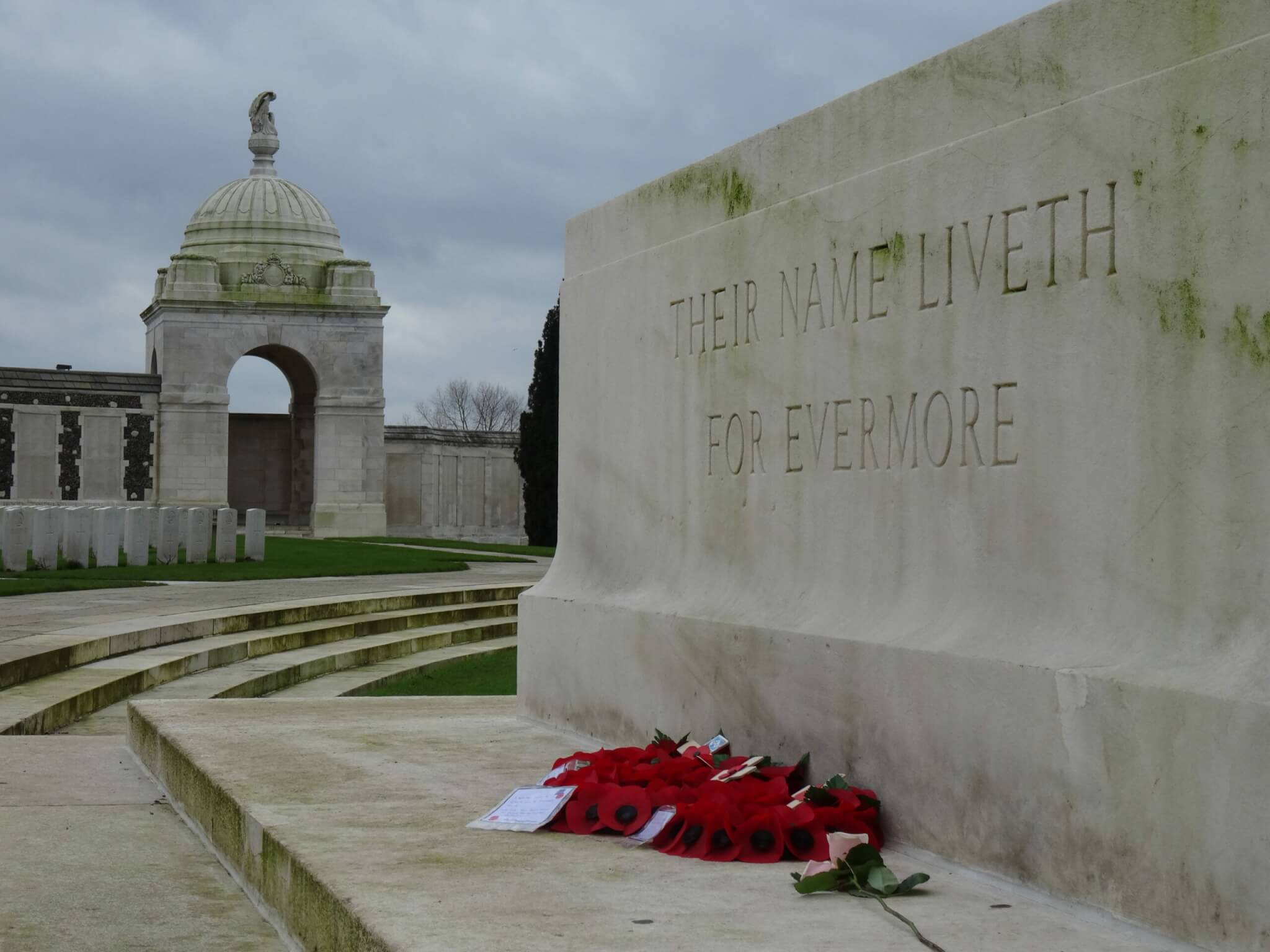 Herinneringssteen op Tyne Cot Cemetery met de tekst "Their name liveth for evermore". Op de achtergrond zerken en een paviljoen